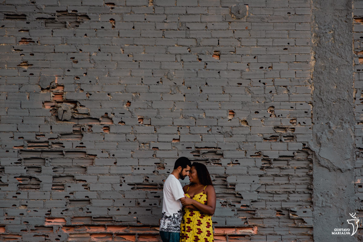 casal se abraçando em frente a parede de tijolos