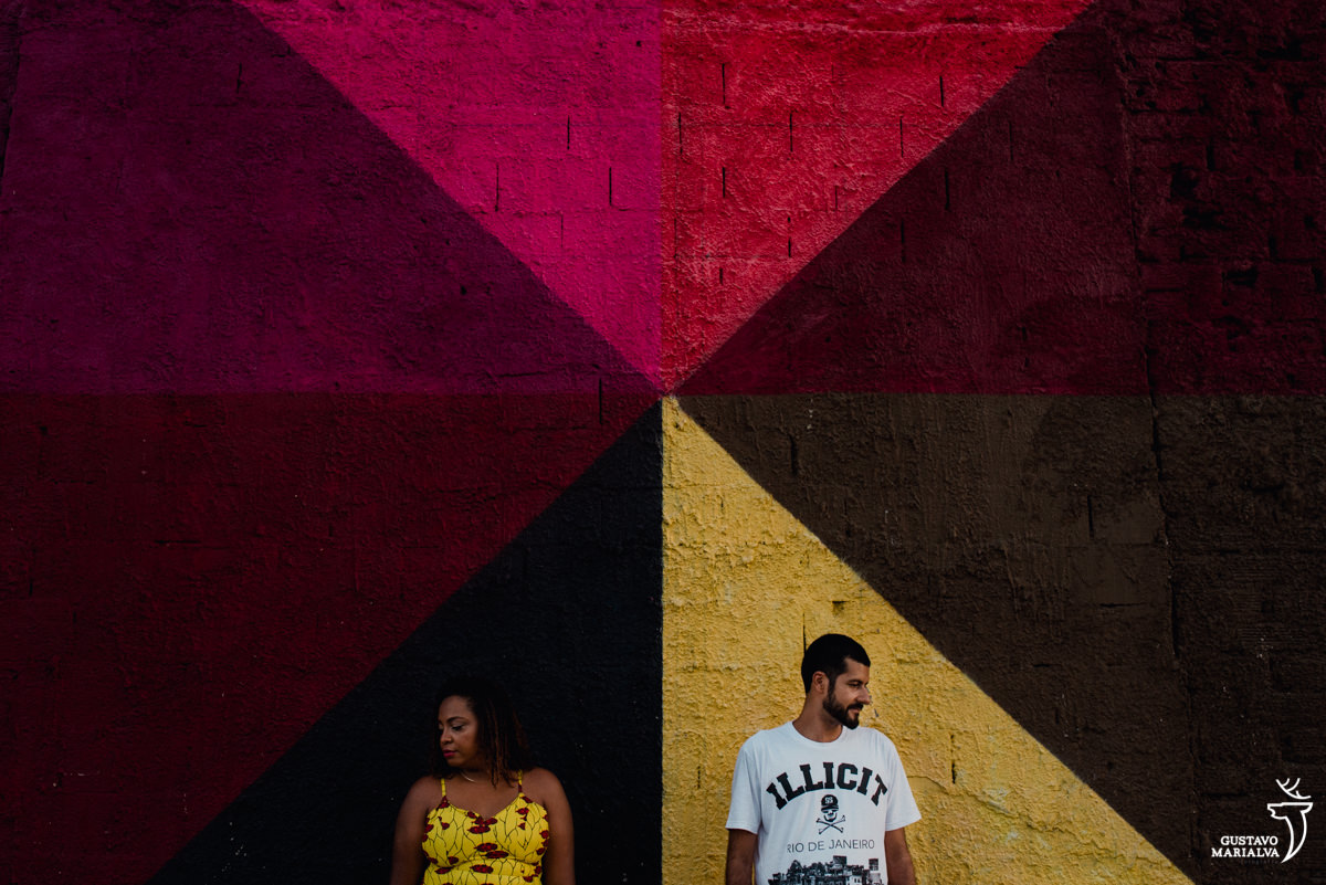 casal posando durante book de casal em frente a painel do Kobra