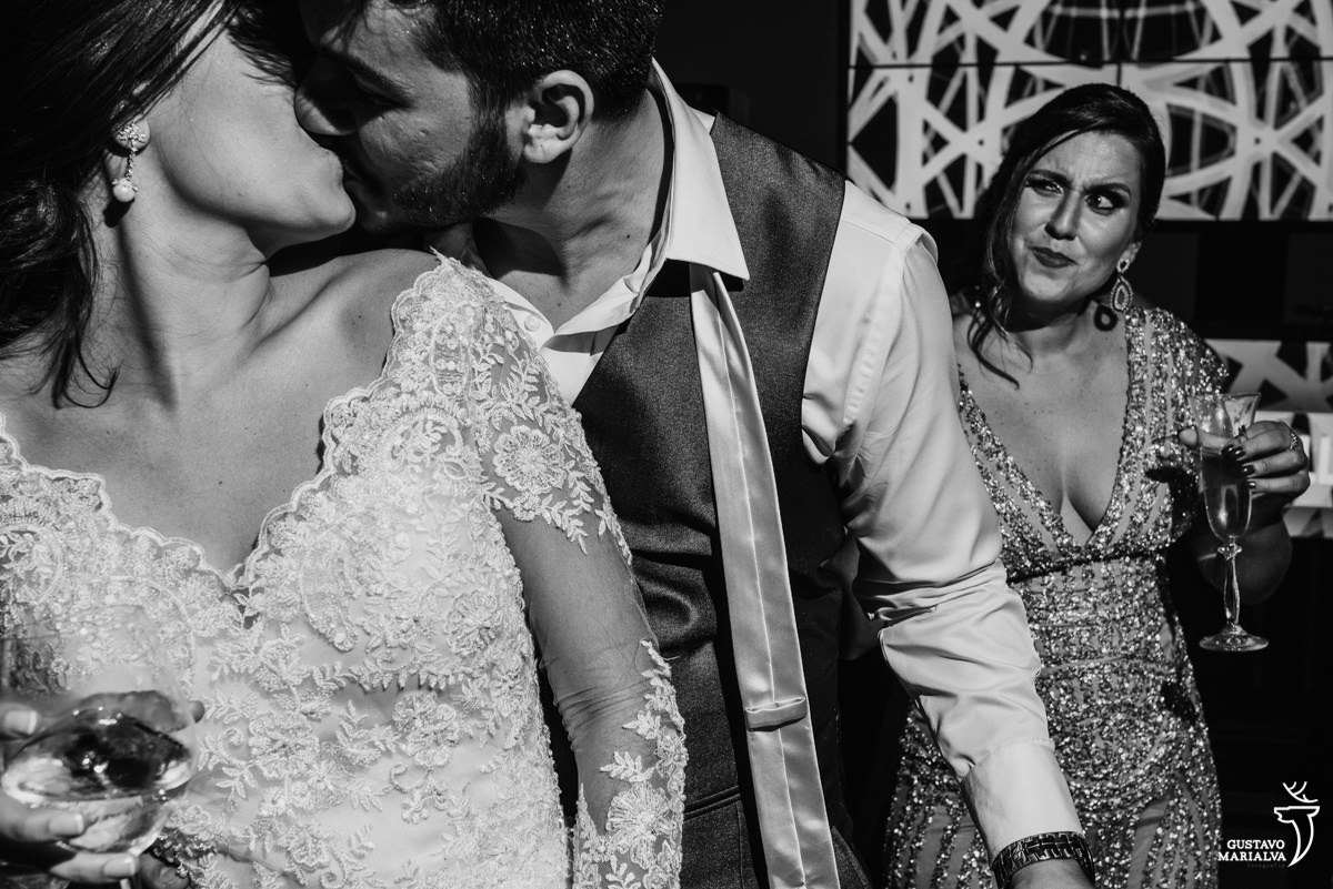 noivos se beijando e madrinha fazendo careta no fundo
