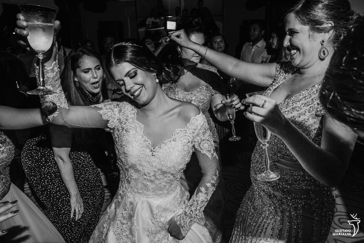 noiva, madrinha e amigas dançando funk segurando uma taça de espumante