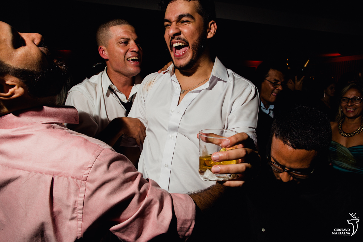 noivo segurando whisky e dançando com amigos