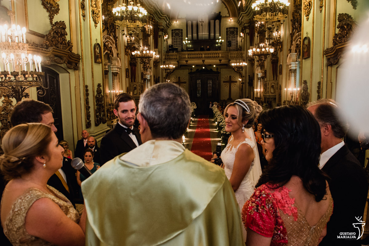 noivos observam a mãe do noivo, emocionada, discursar com os pais dos noivos durante a cerimônia de casamento na igreja são josé no centro do rio de janeiro