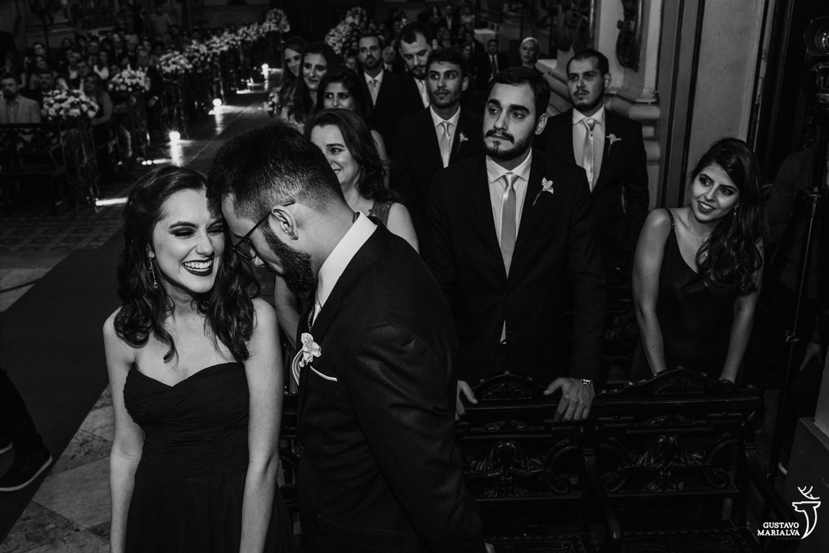 irmã da noiva e padrinhos sorriem emocionados, com padrinhos ao fundo, durante a cerimônia de casamento na igreja são jose no rio de janeiro