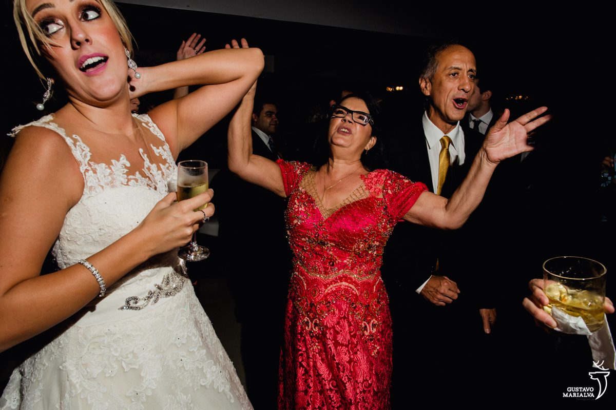 mãe da noiva dança de braços abertos, pai sorri e noiva dança na festa de casamento no clube mandala no rio de janeiro