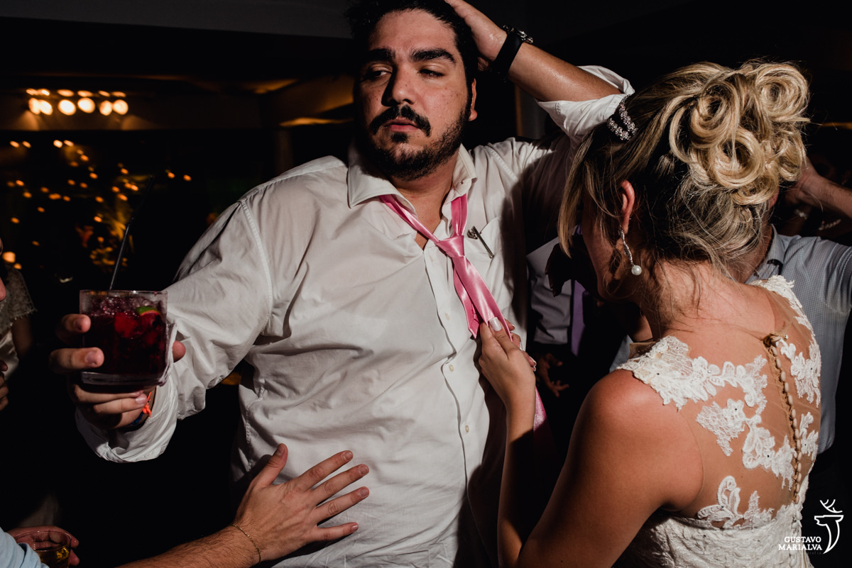 convidado faz cara sensual enquanto a noiva puxa sua gravata na festa de casamento no clube mandala