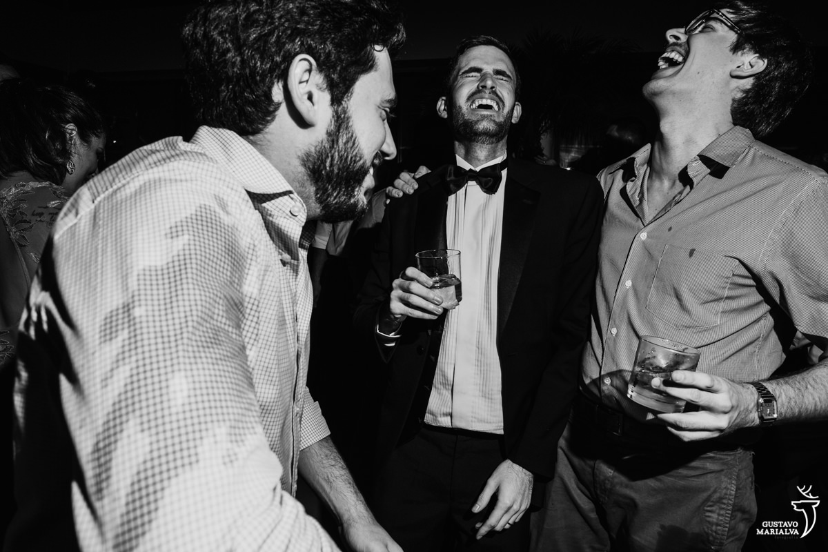 noivo sorri e dança de olhos fechados acompanhado dos amigos
