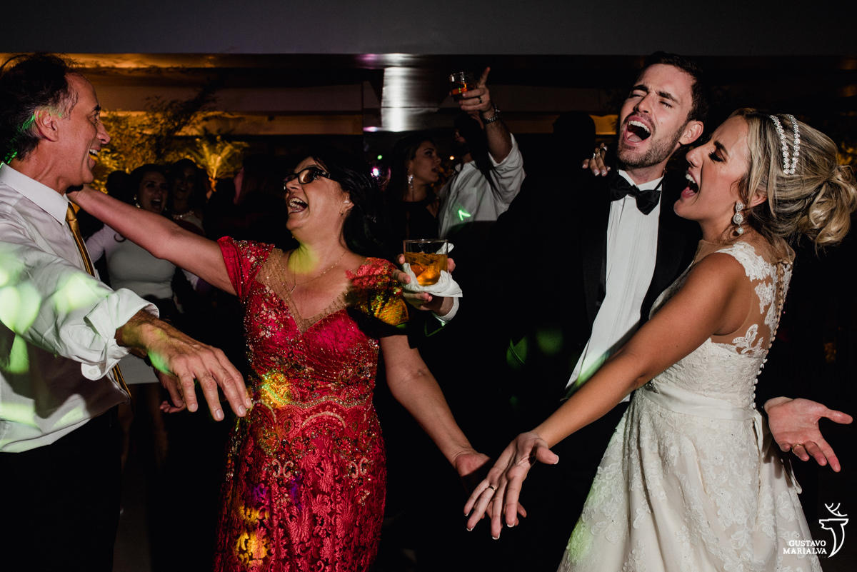 pais da noiva e noivos dançam e gritam comemorando o casamento