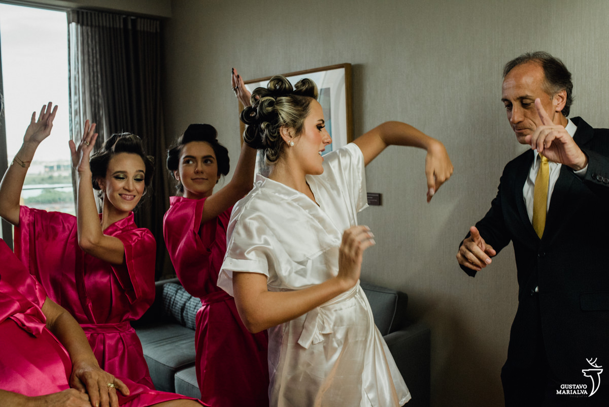 noiva, irmã, madrinha e pai dançando e sorrindo durante o making of do casamento no hotel hilton no rio de janeiro