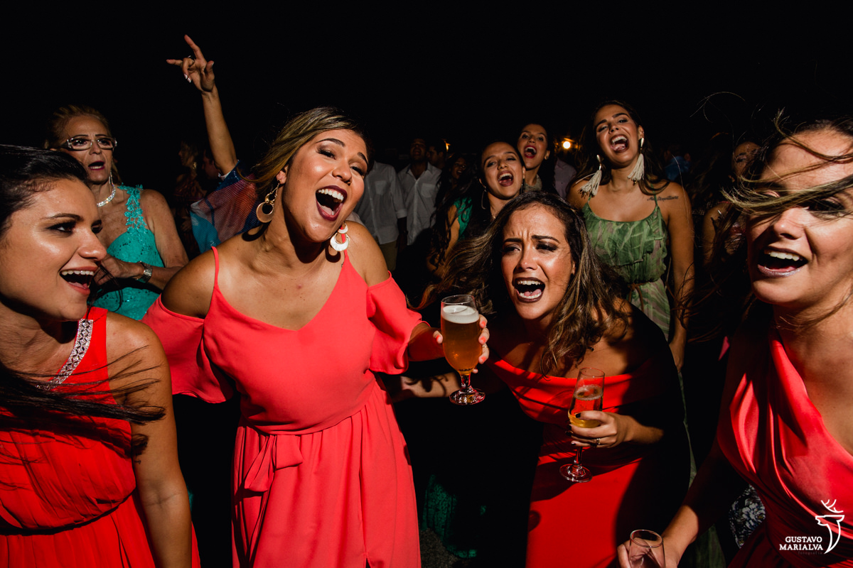 Madrinha com copo de cerveja na mão dança acompanhada de outras amigas na festa de casamento no Uniq Beach Lounge em Búzios