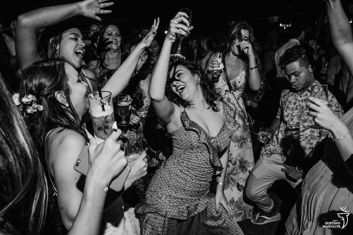 noiva dança funk com as amigas, com as mãos para o alto e copo de bebida nas mãos no Uniq Beach Lounge em Búzios