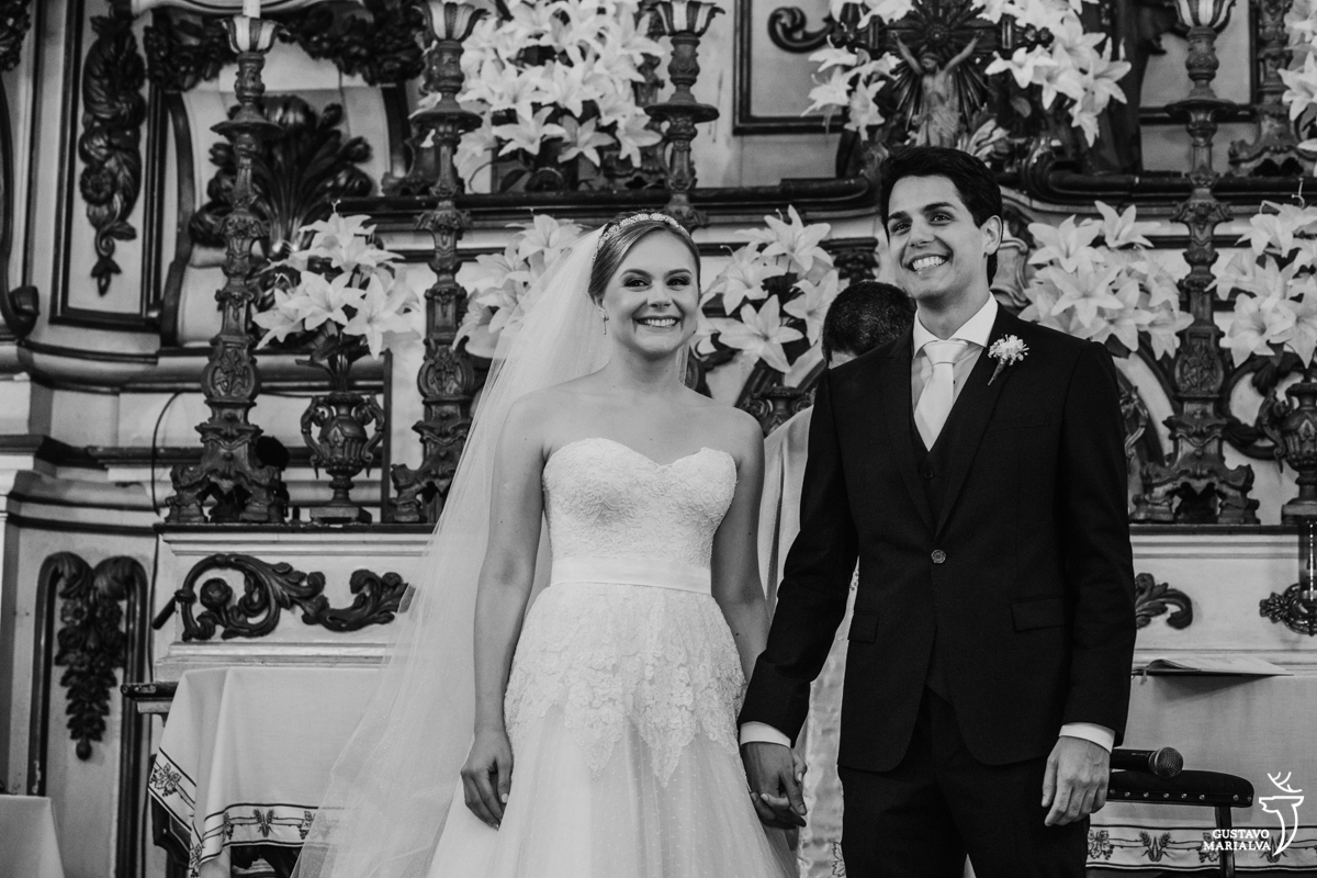 noivos sorriem emocionados e de mãos dadas durante a cerimônia de casamento na igreja são josé