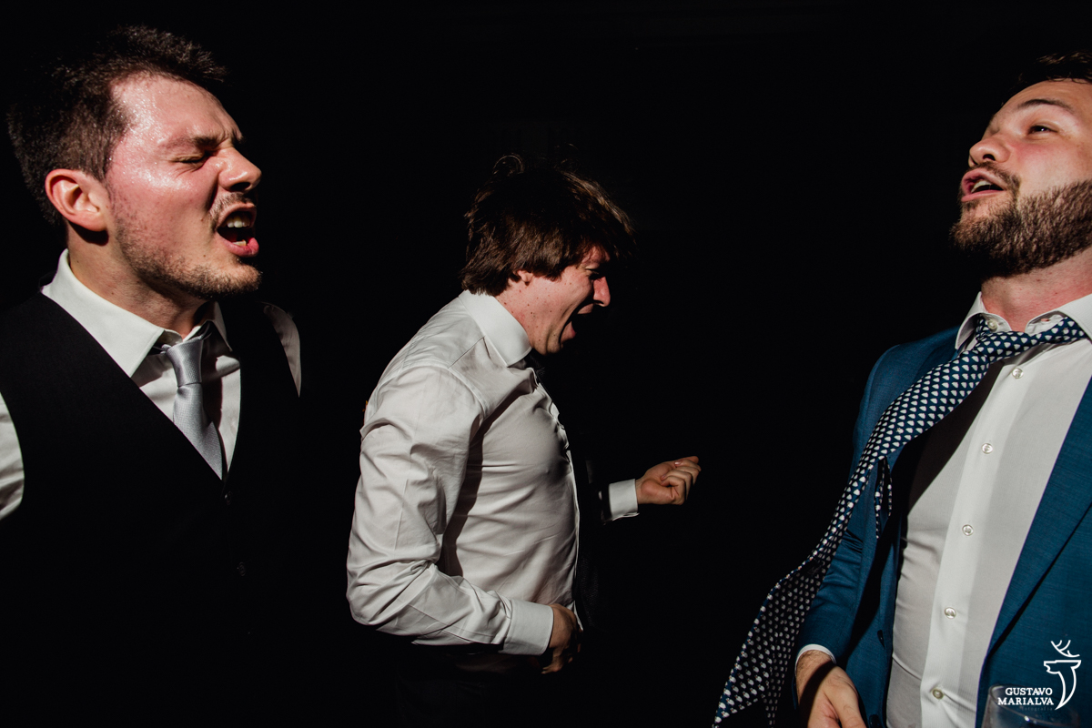 convidado faz air guitar enquanto outros dois convidados cantam animados na festa de casamento na mansão botafogo