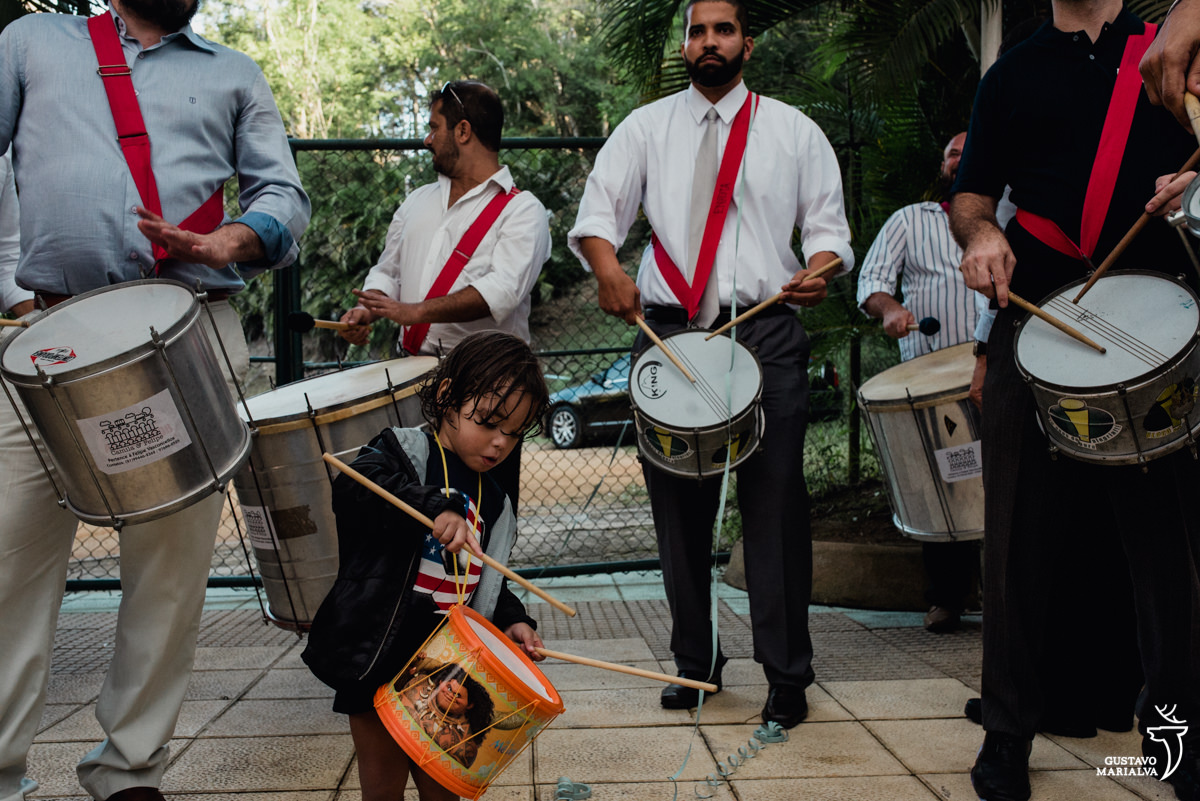 menino toca tambor acompanhado de homens tocando caixa e surdo