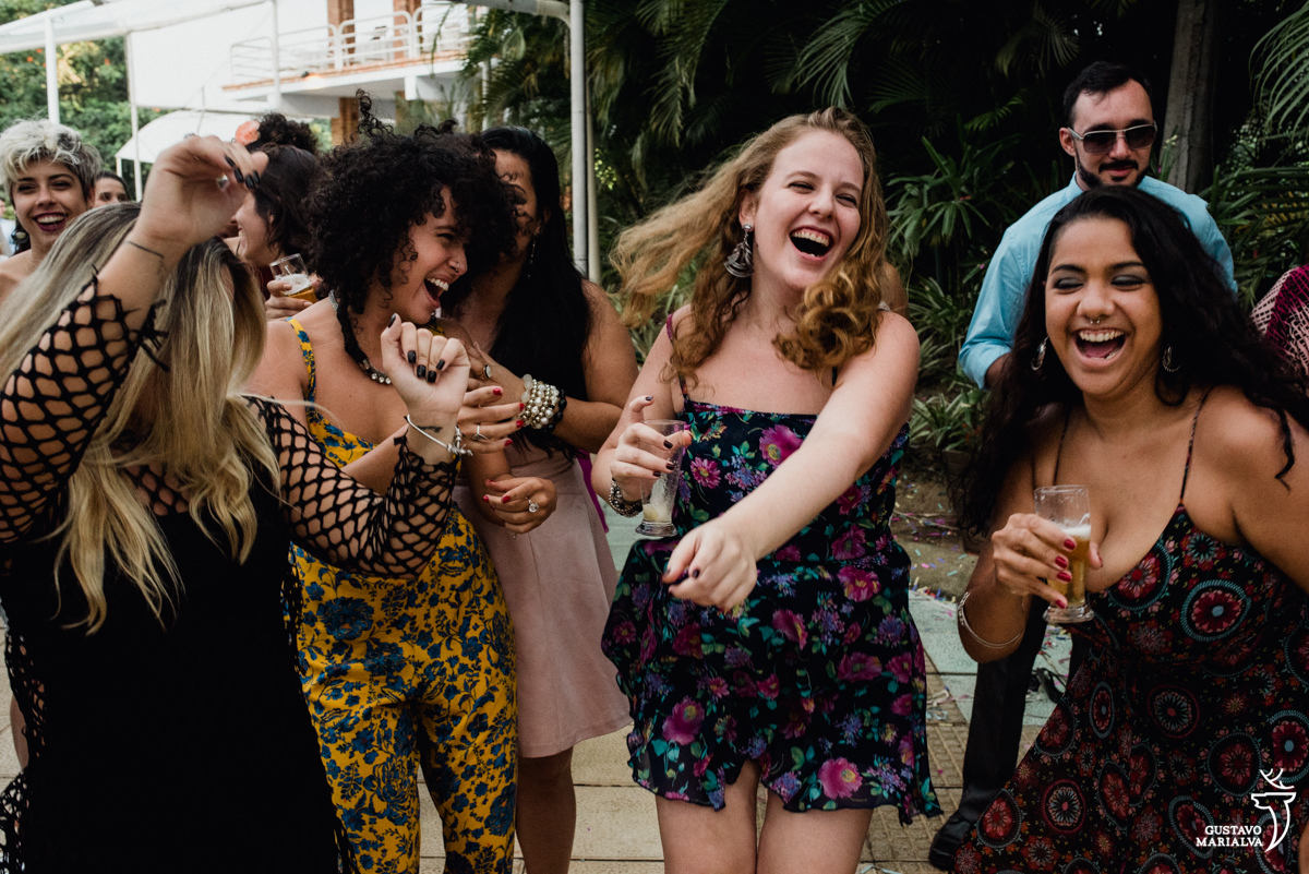 amigas com copo de cerveja nas mãos dançam sorrindo