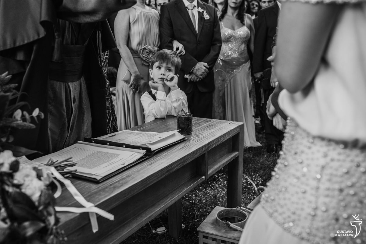 pajem observa a cerimônia de casamento com o dedo na boca