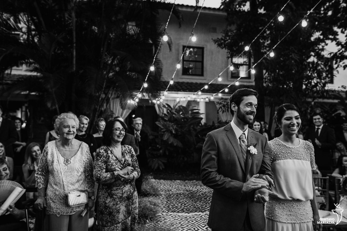 avó do noivo observa a cerimônia de casamento enquanto os noivos sorriem