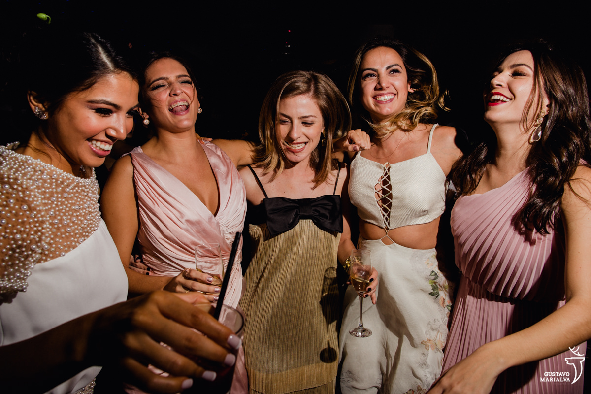 noiva e amigas pulam abraçadas e sorridentes
