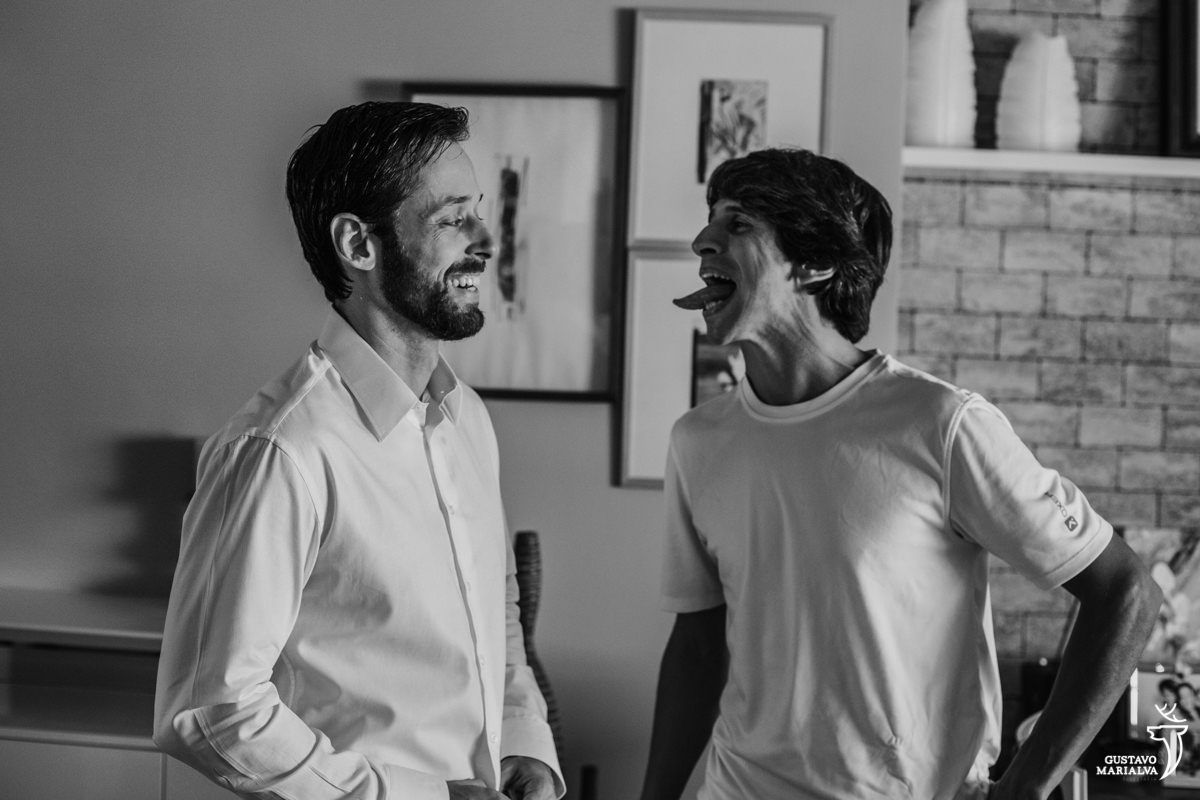 padrinho mostra a lingua para o noivo que sorri enquanto se arruma