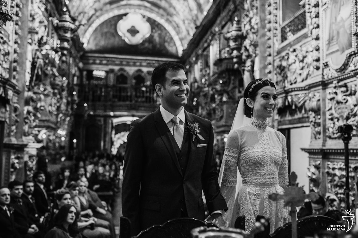 noivo sorriem de mãos dadas durante a cerimônia de casamento
