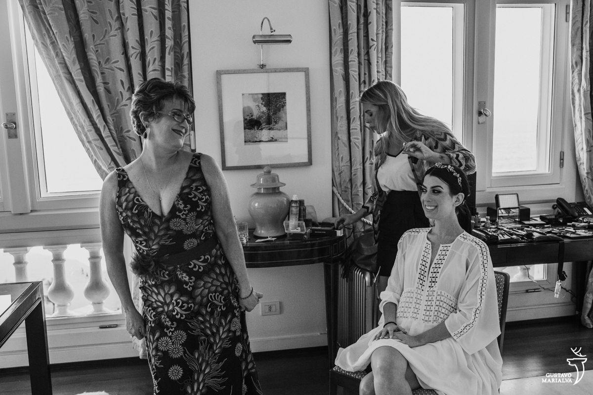 mãe da noiva mostrando o vestido enquanto a noiva sorri durante o making of no hotel copacabana palace