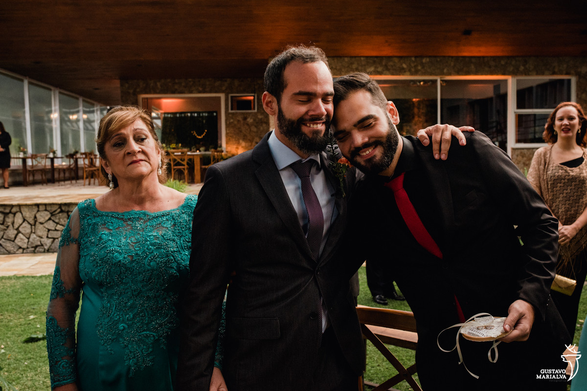 noivo emocionado abraçando irmão e sendo observado pela mãe