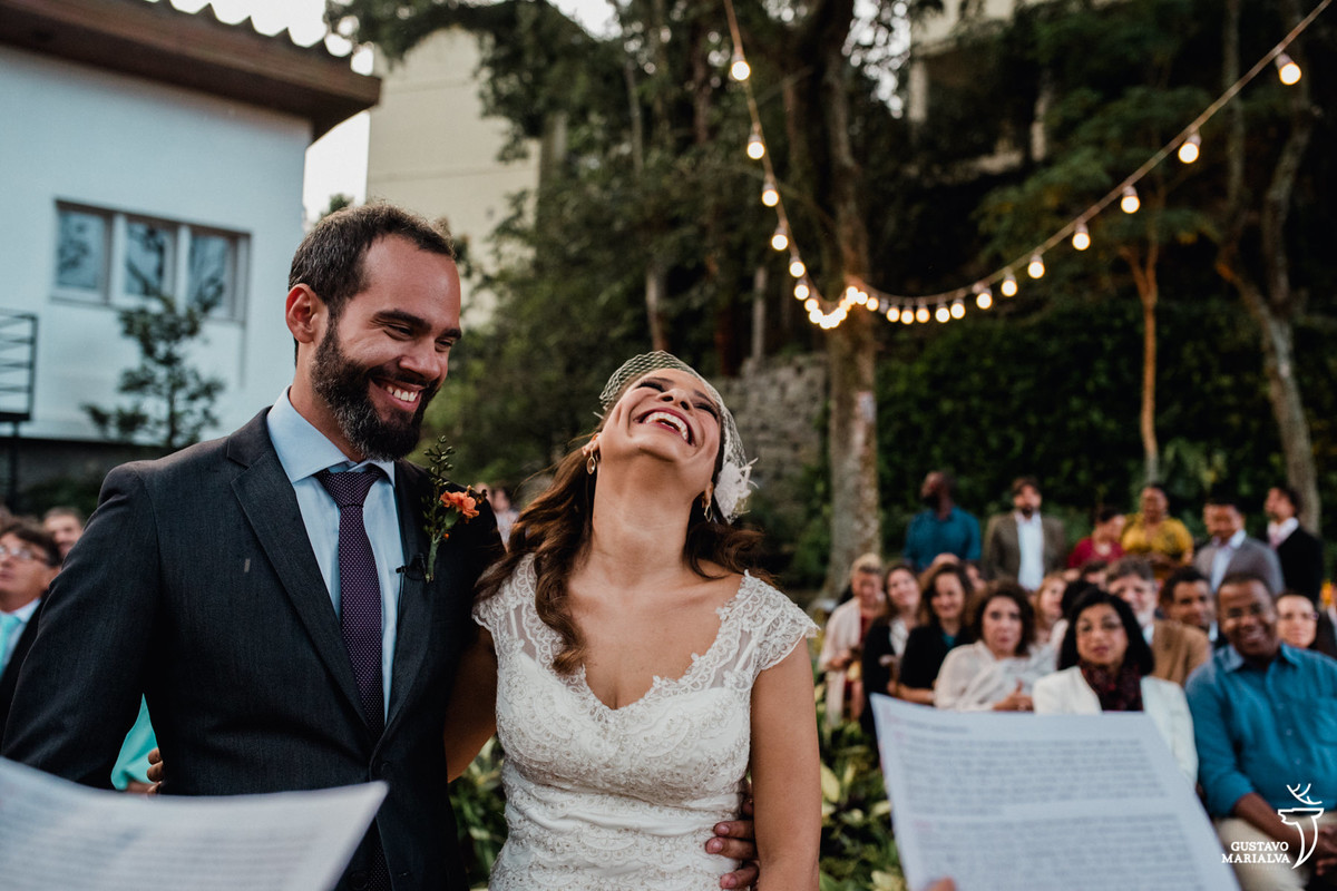 noivos sorrindo com discursos dos amigos durante a cerimônia de casamento
