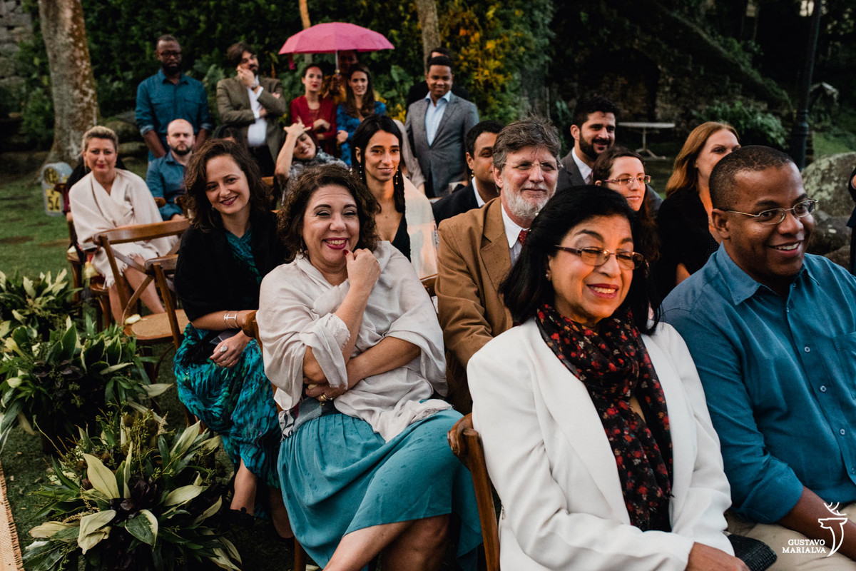 convidados sorrindo emocionados durante a cerimônia de casamento