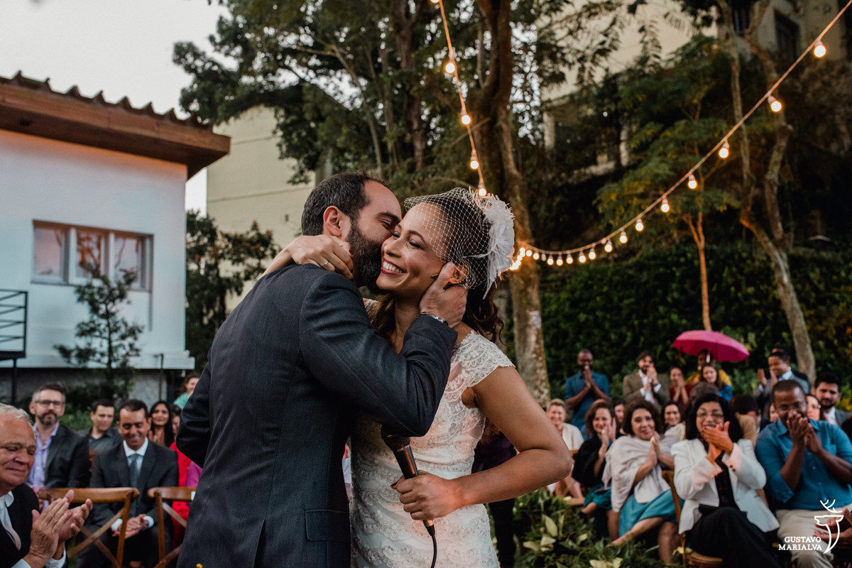 noivo beijando a noiva que segura o microfone