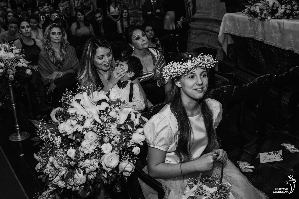 mãe tampa a boca do pajem enquanto daminha sorri
