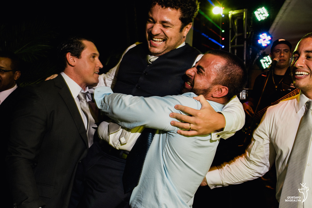 amigo carrega noivo no colo que sorri