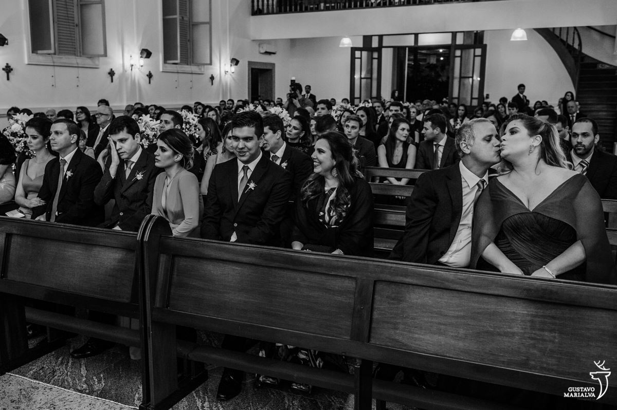 padrinho beija a irmã da noiva enquanto outros padrinhos sorriem durante a cerimônia de casamento