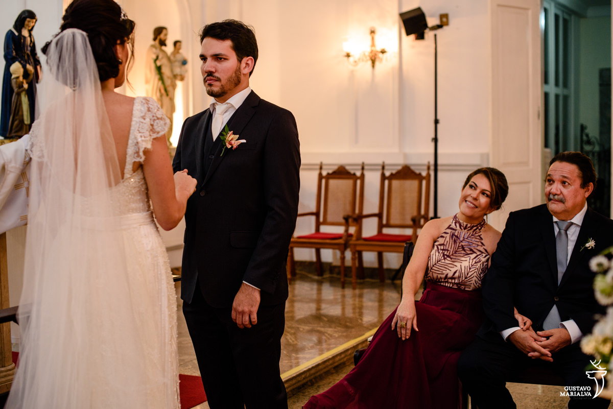 pais do noivo sorrindo emocionados observando a troca de votos