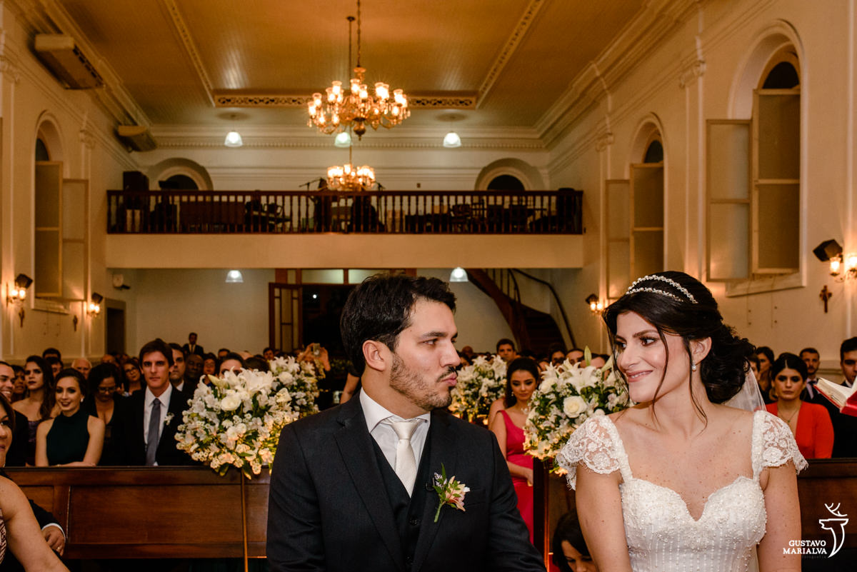 noivo mandando beijo para noiva que sorri durante a cerimônia de casamento