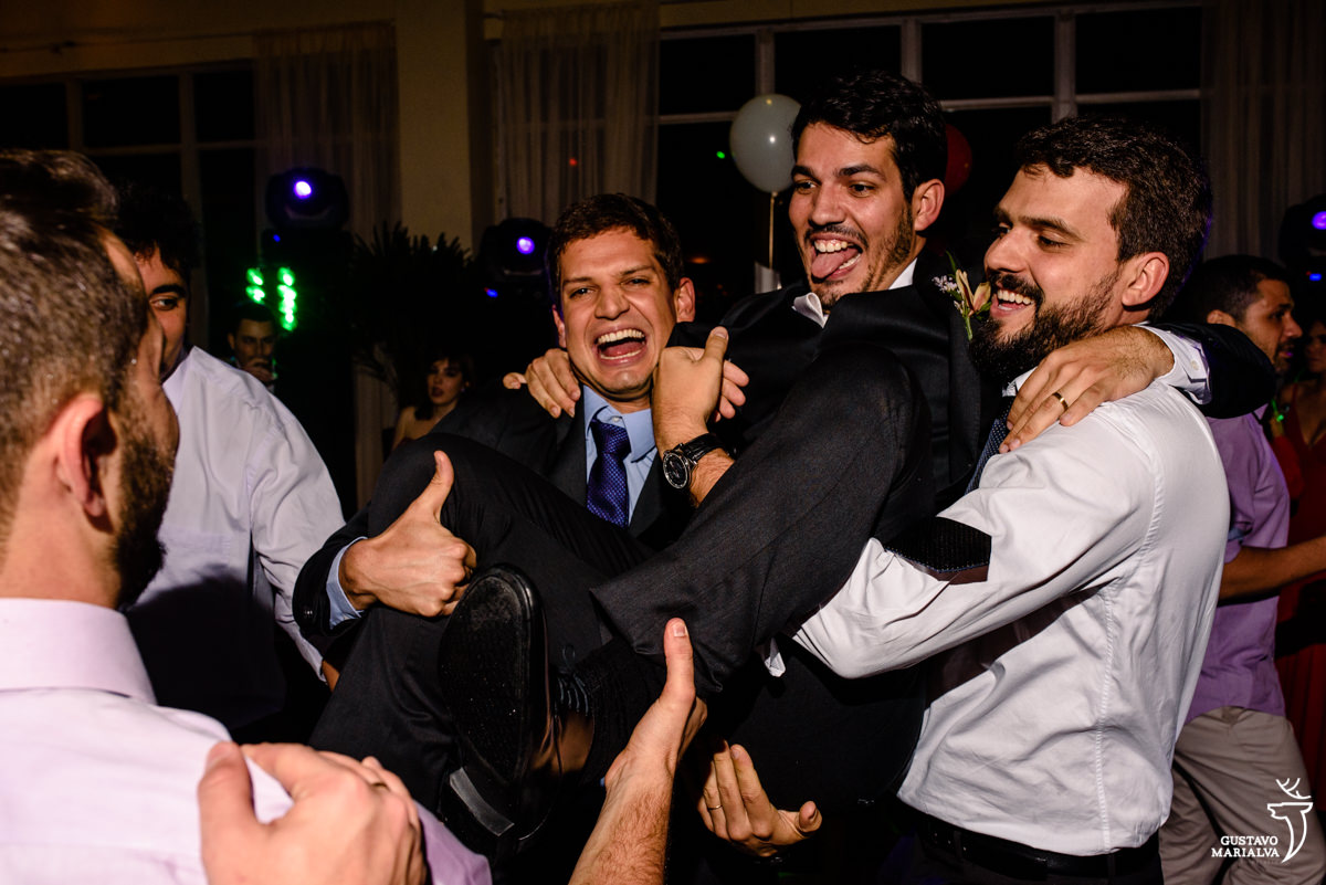 amigos carregam o noivo no colo que coloca a língua para fora