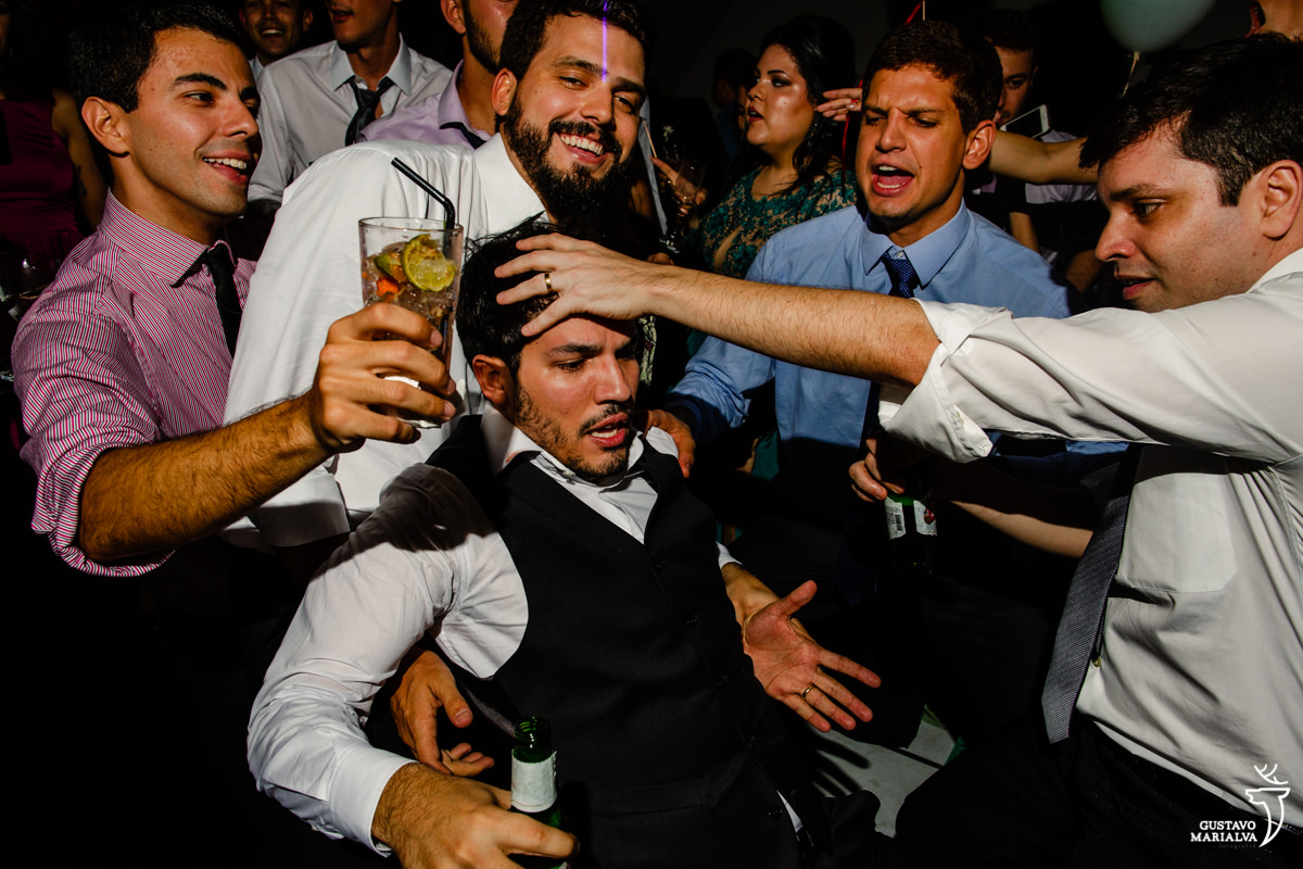 amigos carregam o noivo no colo que faz cara de desesperado