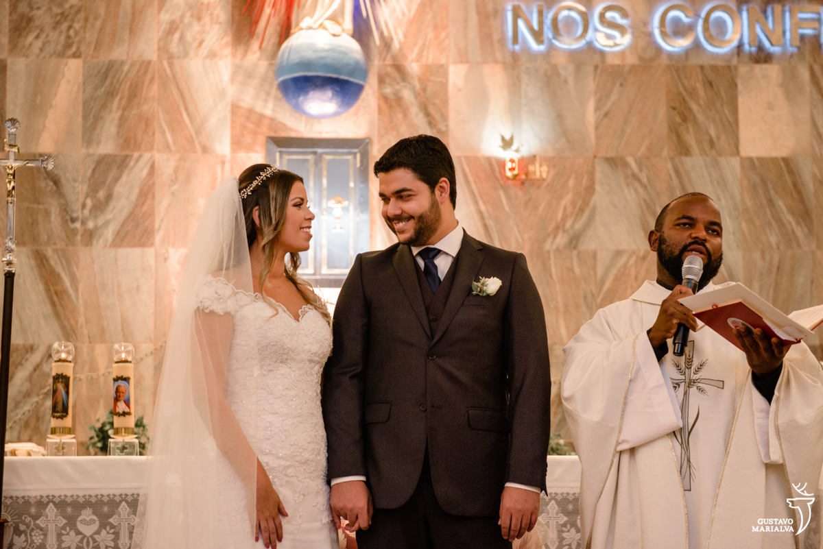 noivos trocam olhares enquanto padre comando a missa