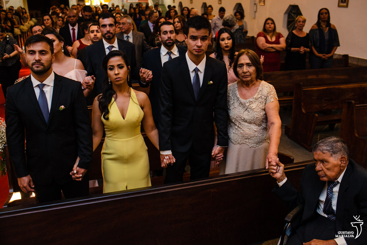 convidados rezam e dão as mãos