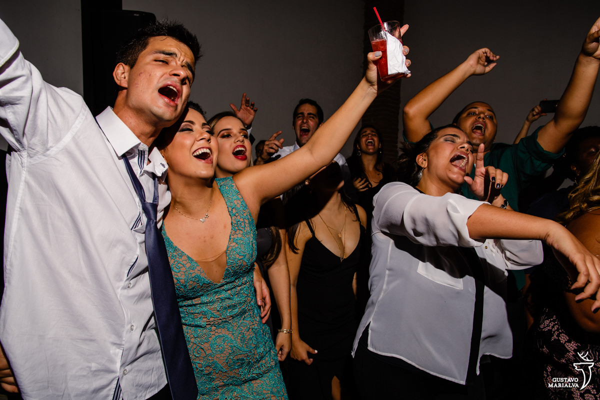 convidados dançam abraçados, cantando, enquanto amigos cantam com braços abertos