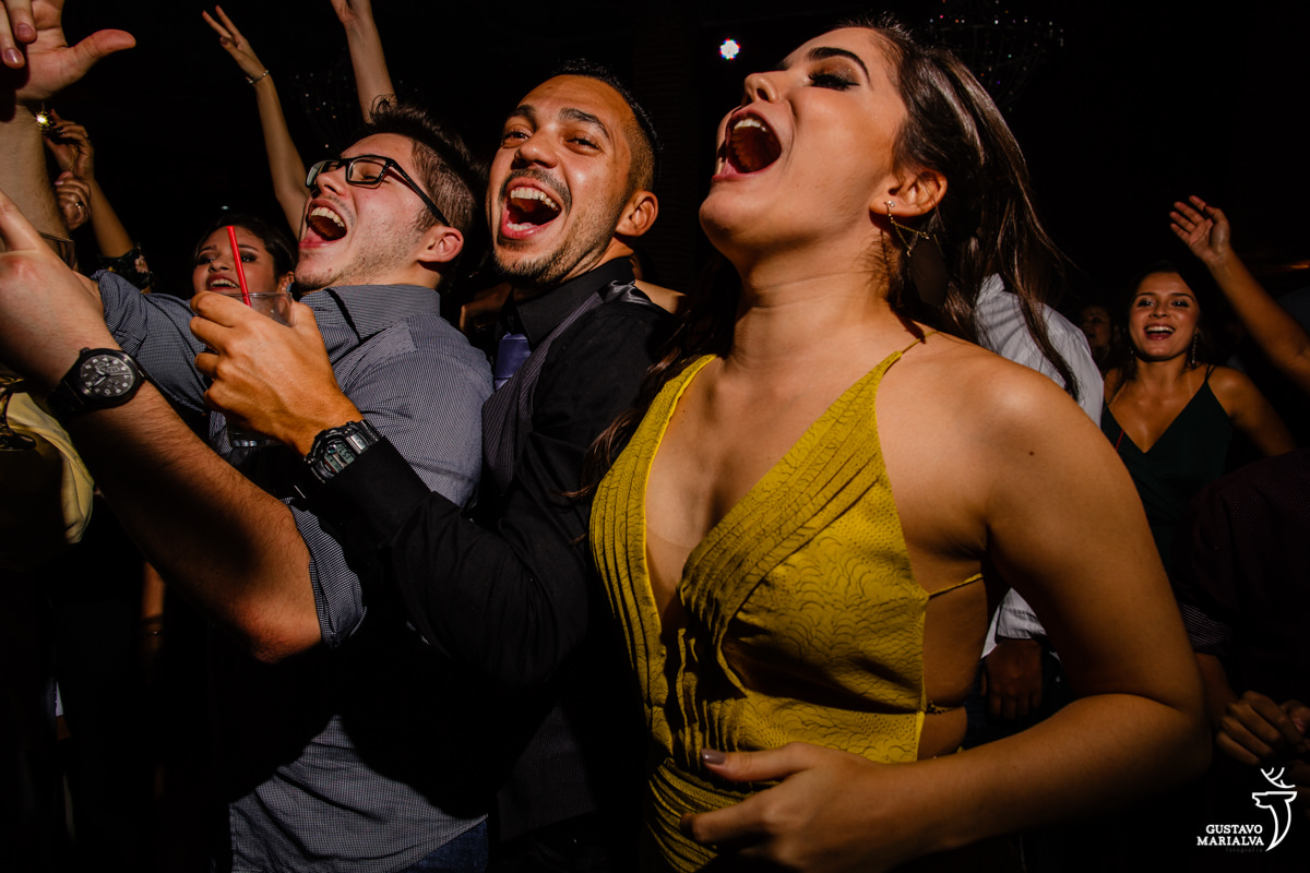 amigos dançam abraçados enquanto mulher pula cantando com a mão na barriga