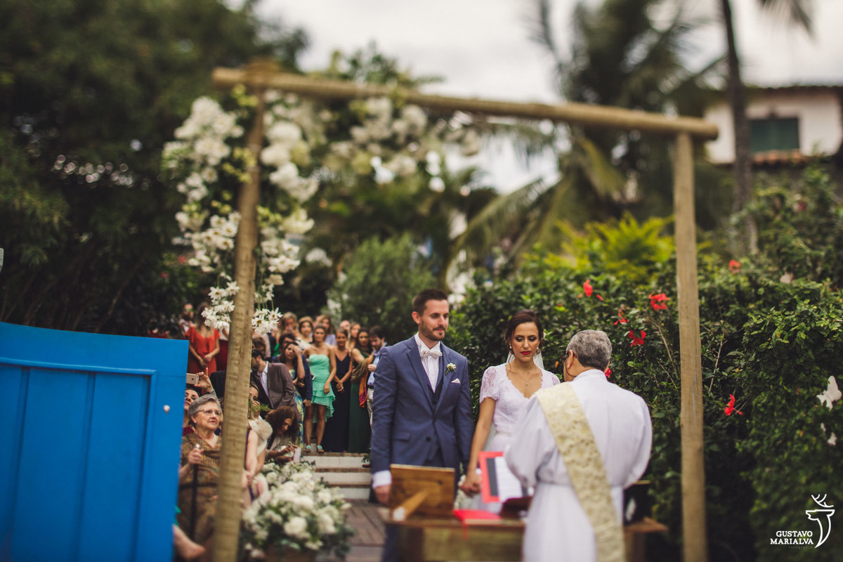 noivos observam a cerimônia com alta feito de madeira e decorado com flores no casamento em búzios