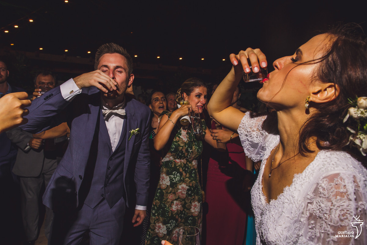 noivos tomam shot de cachaça enquanto convidada faz careta ao fundo