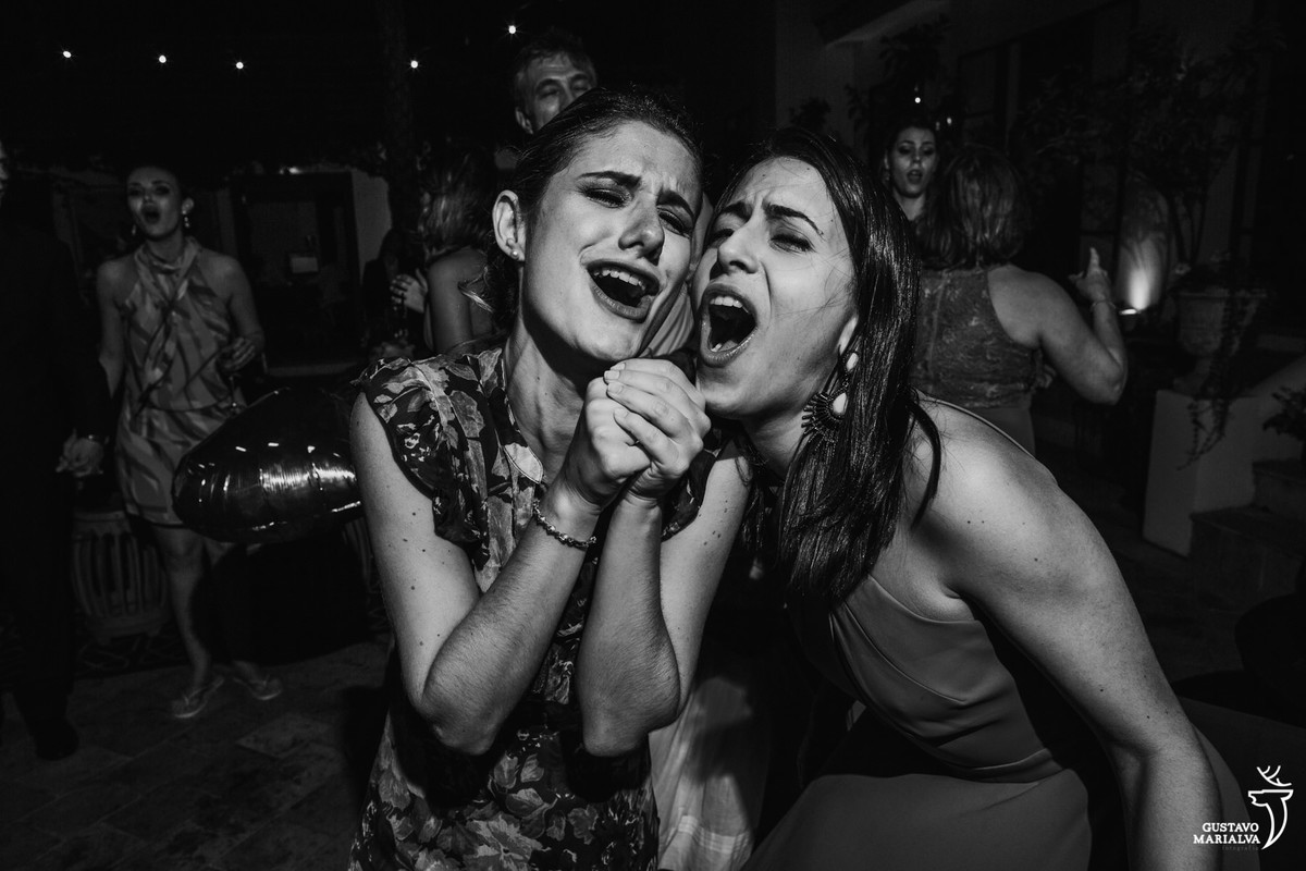 amigas cantam simulando o microfone com as mãos