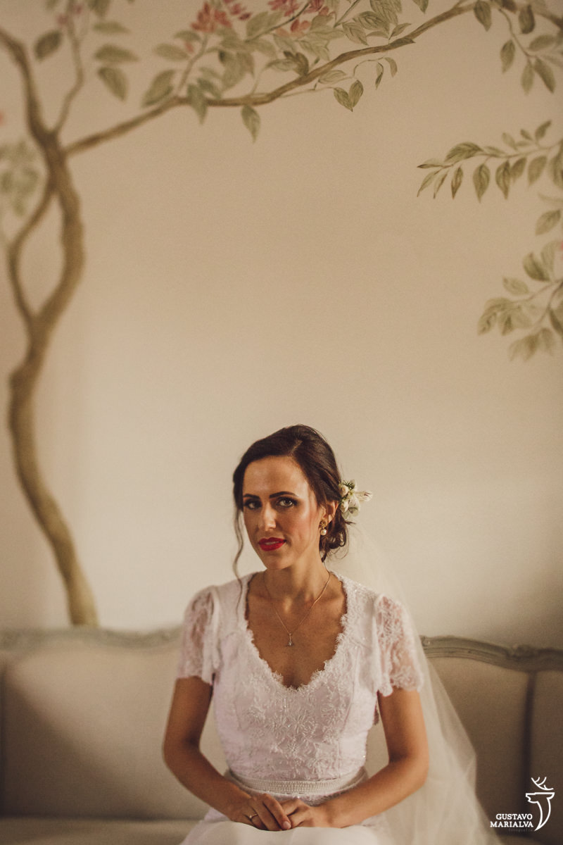 noiva sentada no sofá posando para retrato com árvore pintada na parede ao fundo no hotel vila da santa em búzios