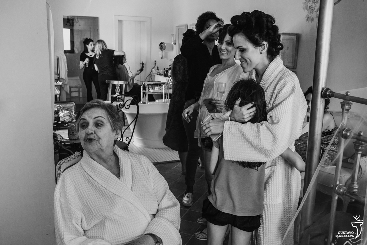 noiva abraça a sobrinha enquanto a avó manda um beijo sendo observada pela neta durante o making of do asamento