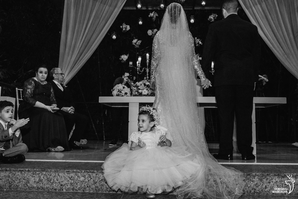 daminha sorrindo sentam em cima do vestido carol hungria da noiva durante a cerimônia de casamento