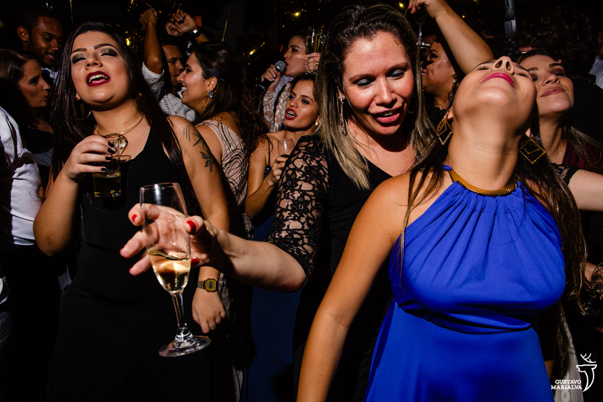 amigas dançam com taça na mão e olhando para cima