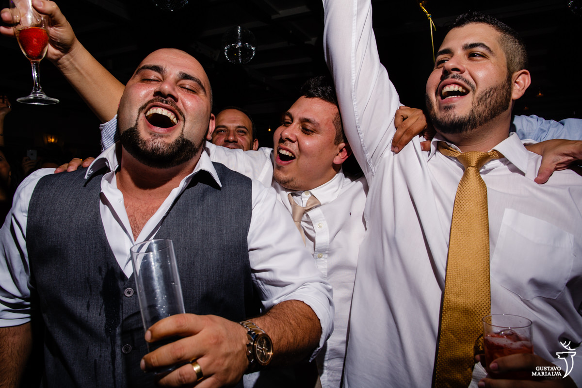 noivo é abraçado por amigos que pulam sorrindo