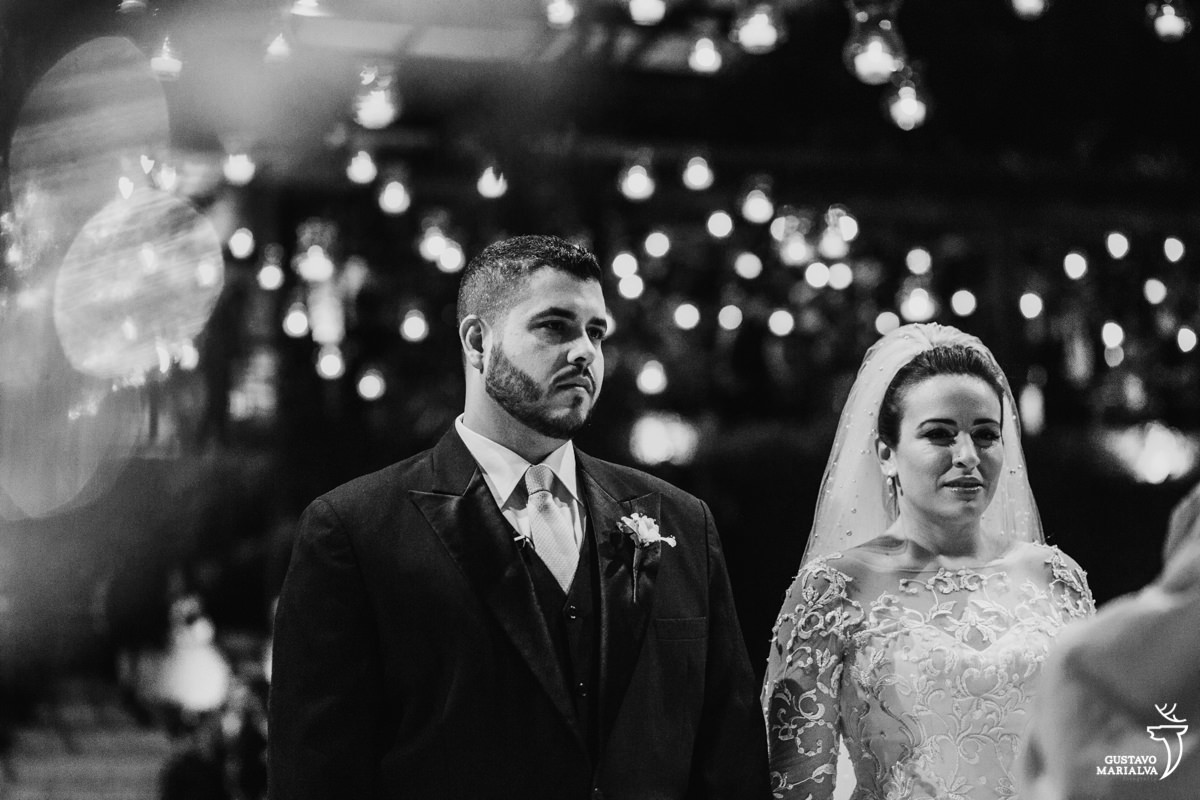 Noivos emocionados prestam atenção na cerimônia de casamento com velas desfocadas ao fundo