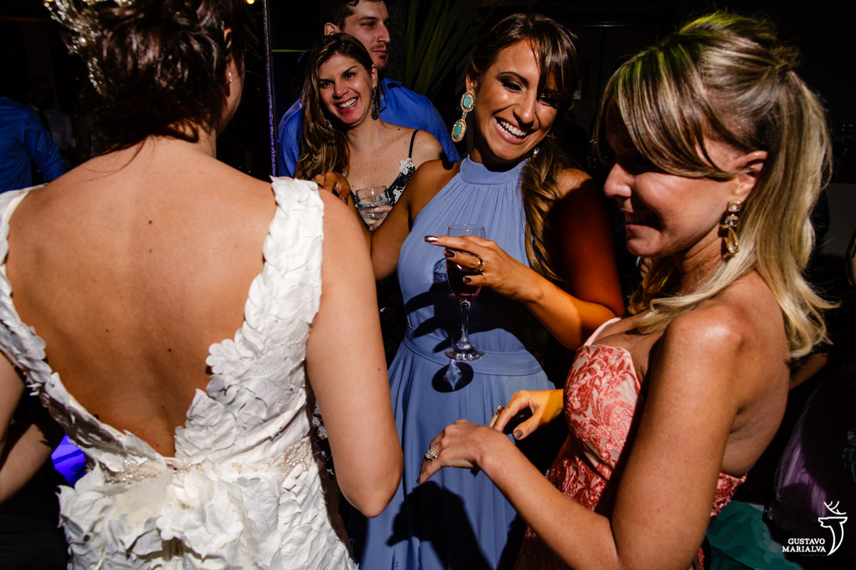 noiva dança com amigas segurando taça de espumante
