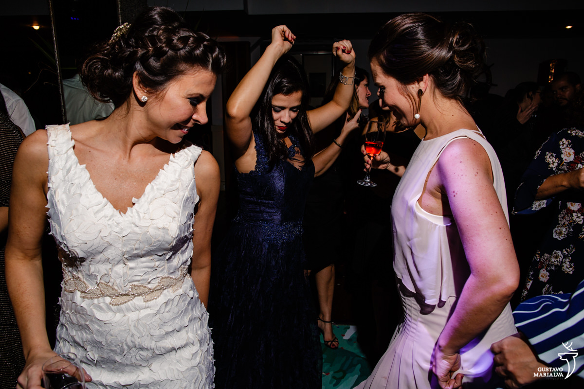 noiva dança com convidada que dança com os braços para cima